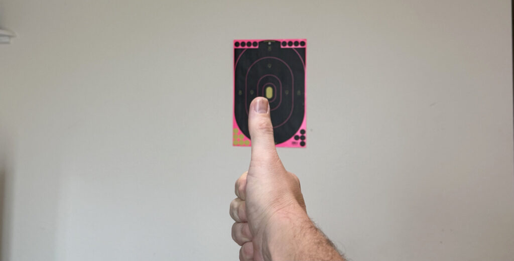 image of a hand with thumb up, against a blurry target